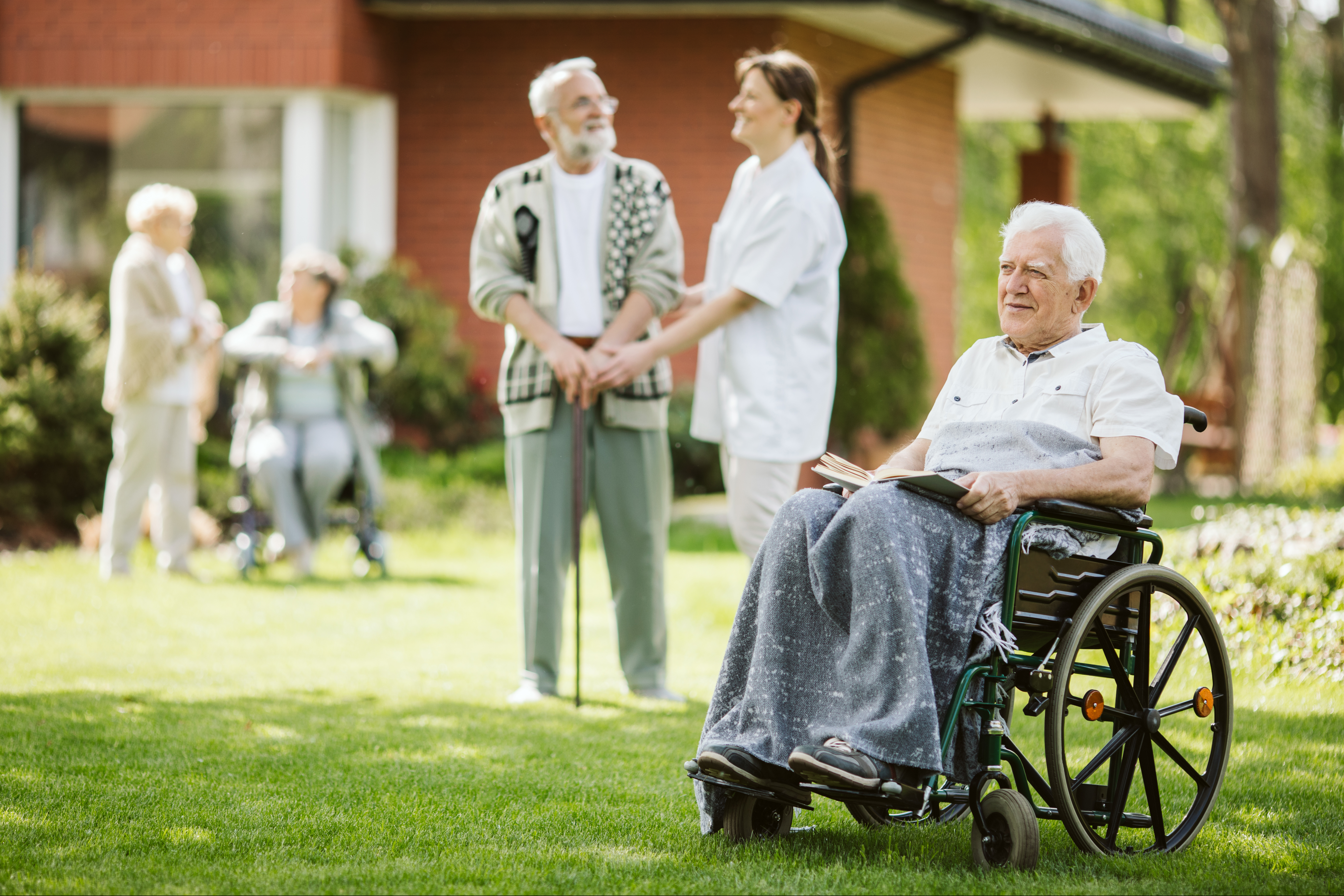 Group of senior patients with caregiver in the garden of nursing home.